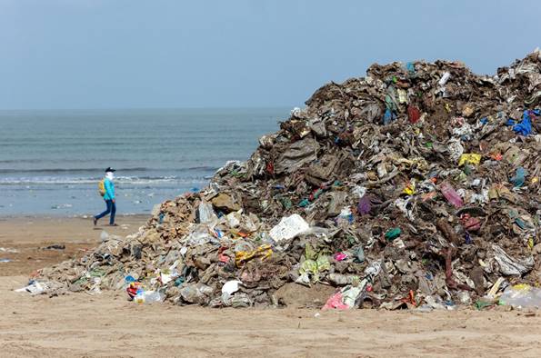 A man walks past a pile of garbage collected at Juhu Beach in Mumbai 